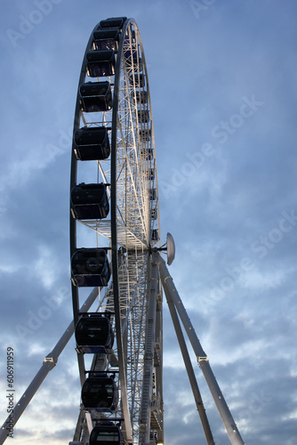 Ferris wheel attraction in the middle of the city with white wheel and blue closed compartments with lights © Maria de la Pe/a