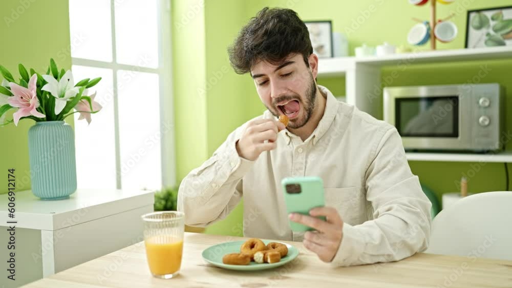 Young hispanic man having breakfast using smartphone at dinning room Young hispanic man having breakfast using smartphone at dinning room