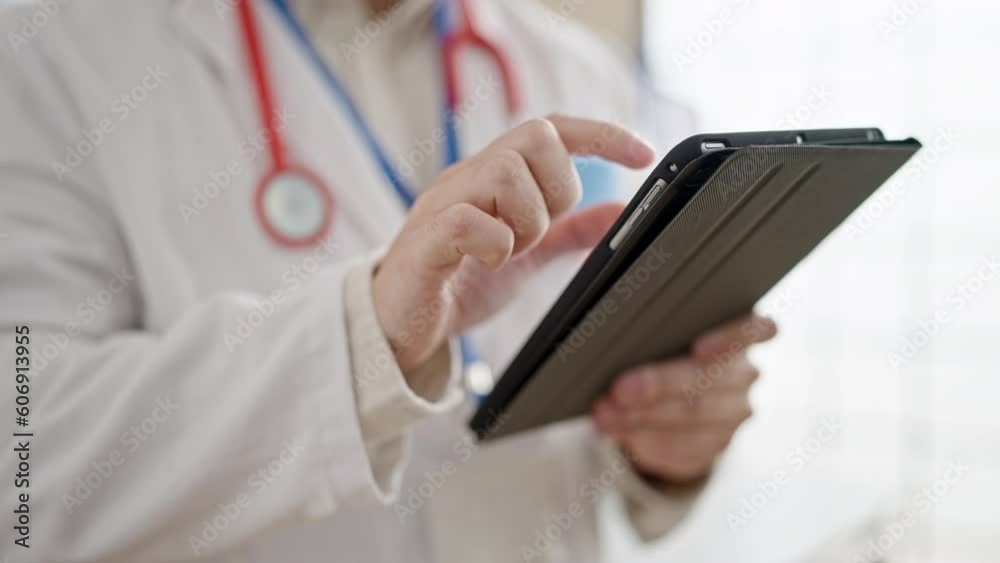 Young hispanic man doctor using touchpad at clinic