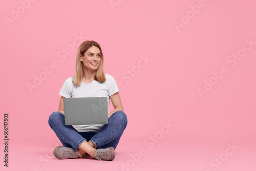 Happy woman with laptop on pink background. Space for text
