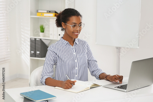 Smiling African American intern working at white table in office photo