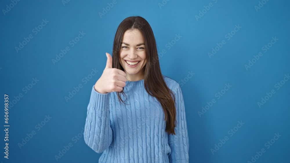 Young caucasian woman smiling with thumbs up over isolated blue background Young caucasian woman smiling with thumbs up over isolated blue background