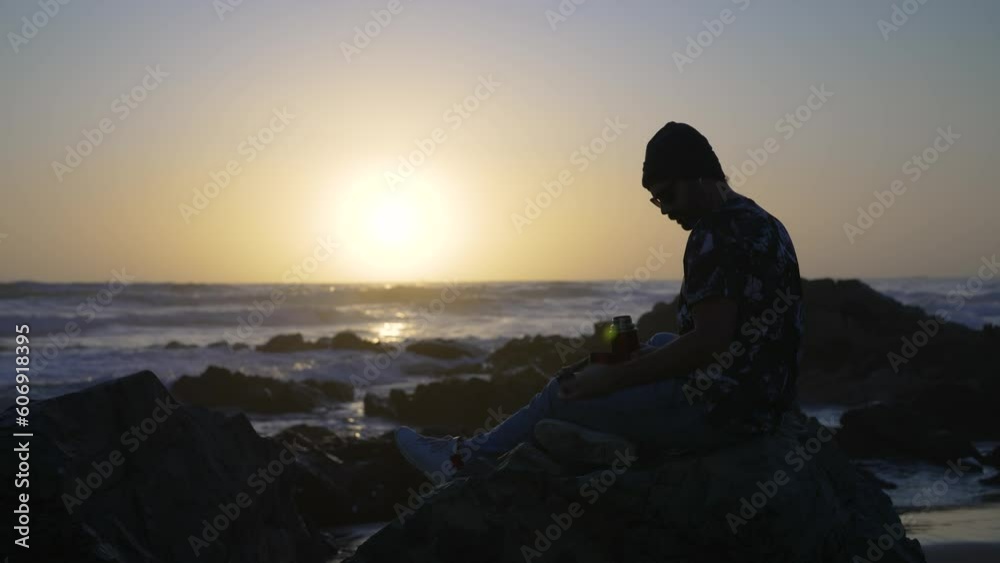silhouette mature man sitting on the rock on the beach shore drinking coffee relaxed silhouette mature man sitting on the rock on the beach shore drinking coffee relaxed