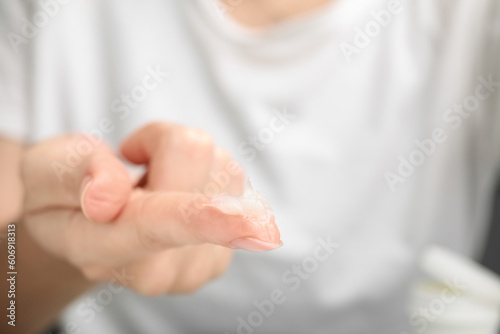 Woman with sample of cosmetic petrolatum on her finger, closeup. Space for text