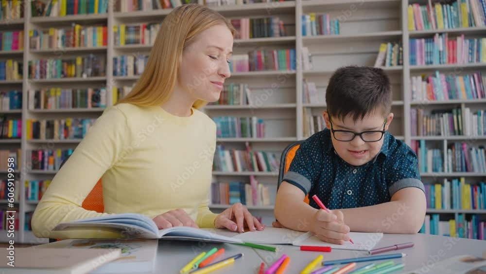 Adorable school boy with Down syndrome, engaged in learning writing with educational psychologist Adorable school boy with Down syndrome, engaged in learning writing with educational psychologist