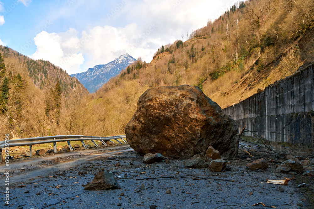 A huge rock fell from the mountains onto the road, destroying the asphalt and blocking half of the roadway