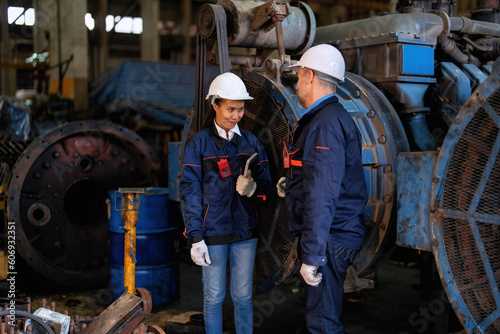 Two technical workers working in a maintenance shop checking heavy engine industry factory 