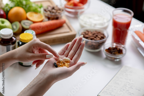 Woman professional nutritionist checking dietary supplements in hand, surrounded by a variety of fruits, nuts, vegetables, and dietary supplements on the table photo