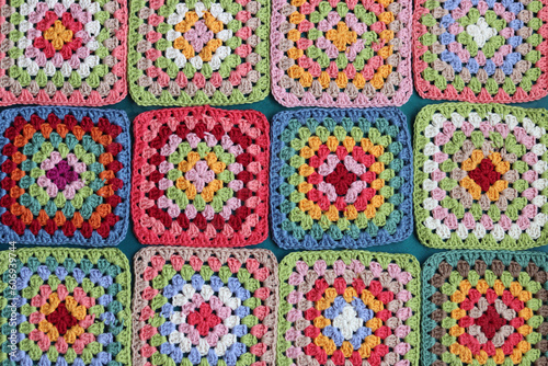 Granny squares on blue background. Top view with copy space. Handmade crocheting, needlework and handicraft concept - crocheting accessories