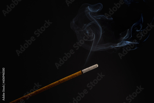 burning incense stick smoldering on a black background