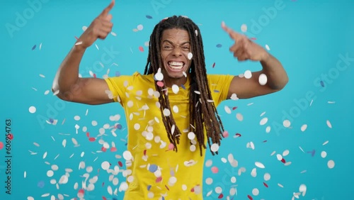 Happy latin man with dreadlocks surrounded by confetti in air