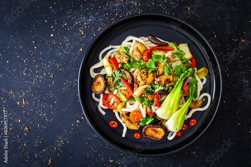 Chicken nuggets with noodles and stir fried vegetables on black table 