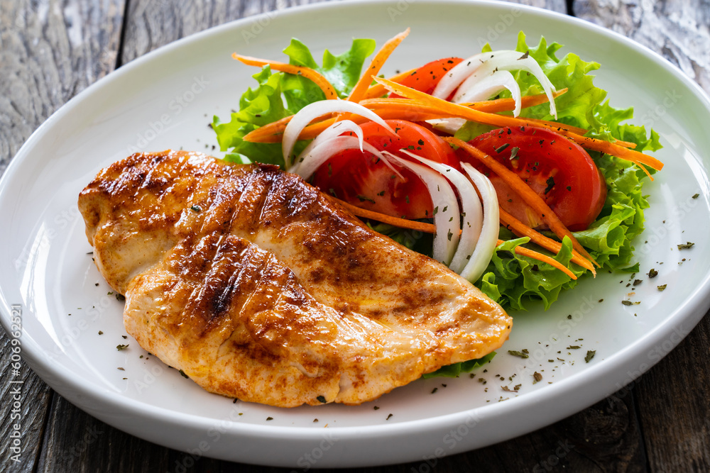 Grilled chicken breast and fresh vegetables on wooden table
Grilled chicken breast and fresh vegetables on wooden table
