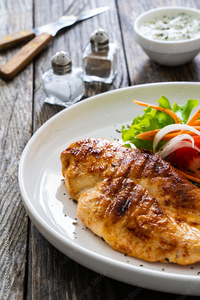 Grilled chicken breast and fresh vegetables on wooden table
Grilled chicken breast and fresh vegetables on wooden table