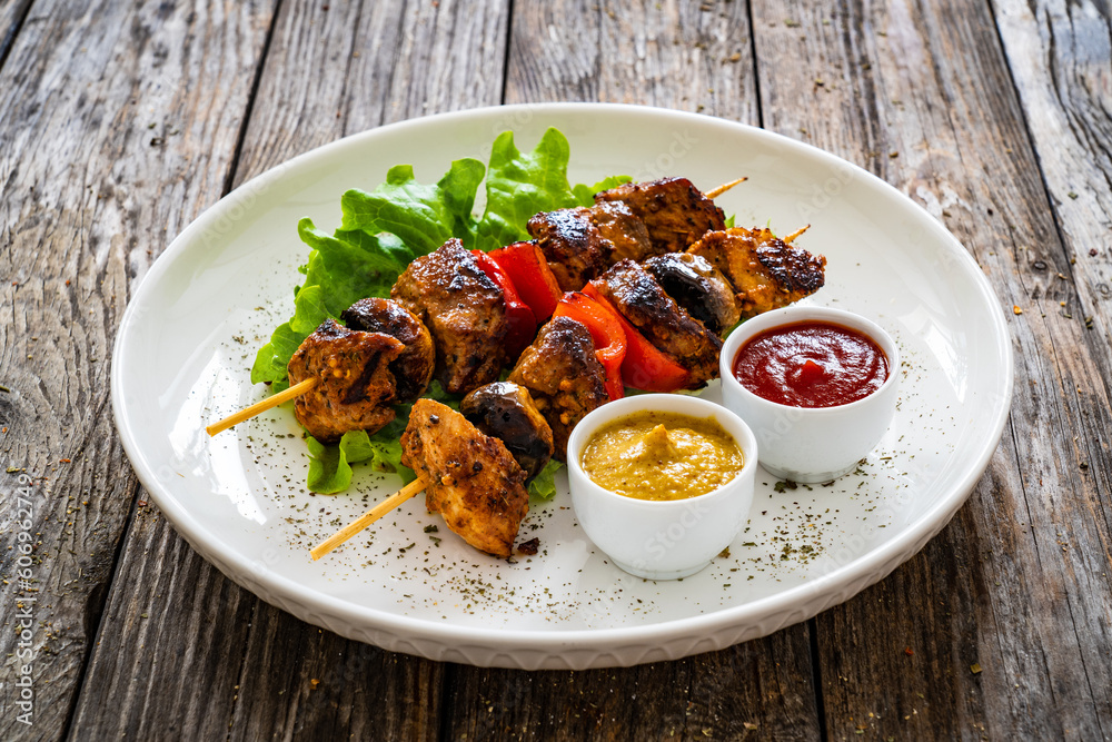 Meat skewers - grilled meat with vegetables on wooden background
