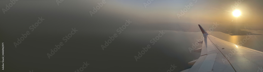 Wide template with space for text. Background of sunset. Wing of airplane, view from aircraft, flight. Horizontal backdrop with place for inscription. Idea for travel service, aviation, transportation