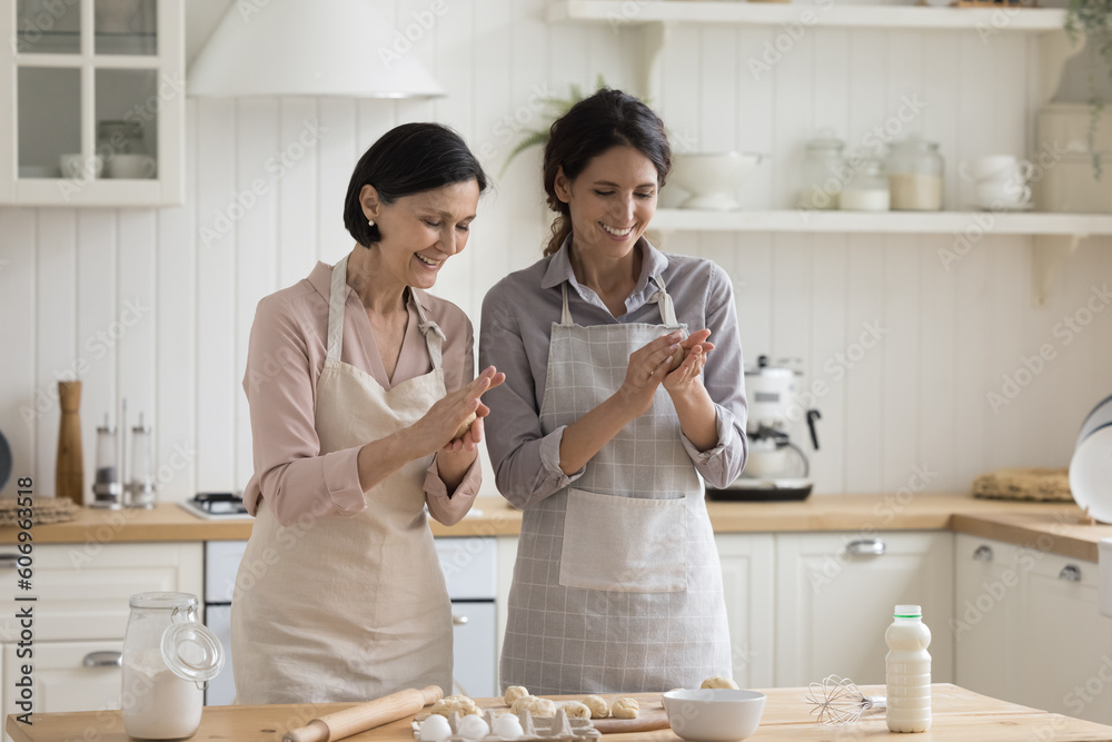 Φωτογραφία Cheerful positive mature mom and adult child woman baking pies, biscuits, shapin