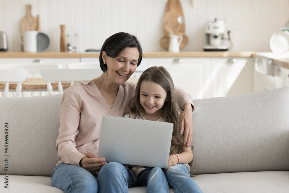 Φωτογραφία Happy mature grandma and cute little grand child girl using laptop computer at h