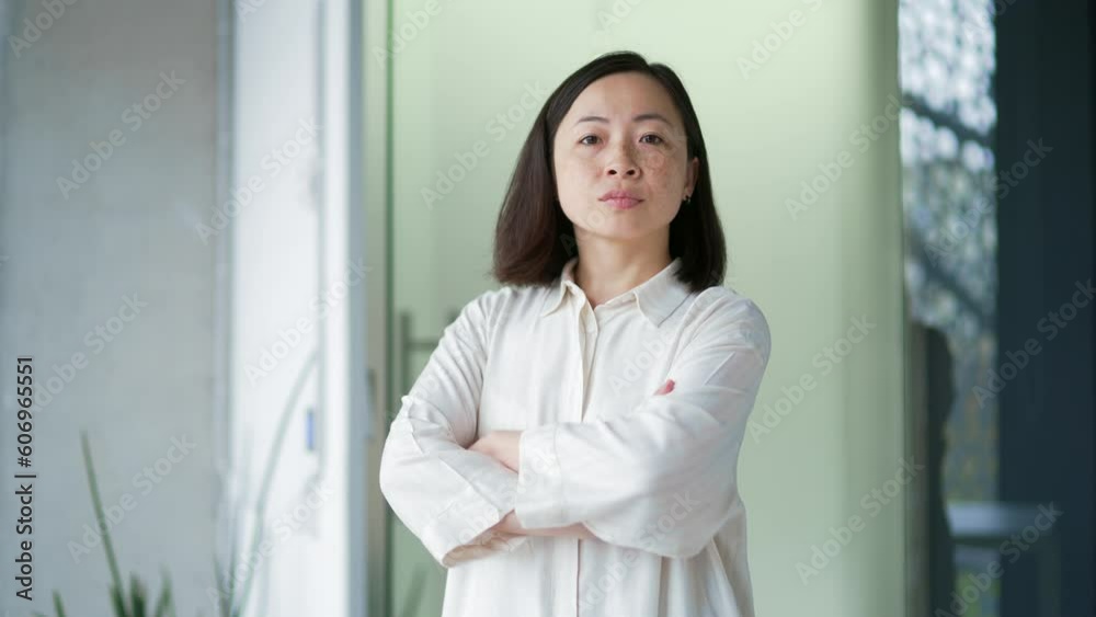 Portrait of confident Asian female employee standing in modern office with crossed arms. A stylish serious blonde businesswoman in a shirt poses for a headshot business portrait. A successful manager Portrait of confident Asian female employee standing in modern office with crossed arms. A stylish serious blonde businesswoman in a shirt poses for a headshot business portrait. A successful manager