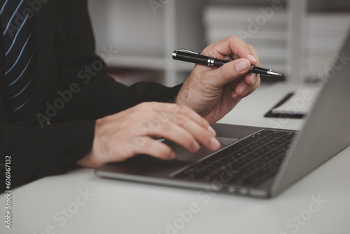 Person typing on laptop keyboard, businessman working on laptop, he is typing messages to colleagues and making financial information sheet to sum up the meeting.