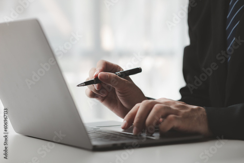 Person typing on laptop keyboard, businessman working on laptop, he is typing messages to colleagues and making financial information sheet to sum up the meeting.