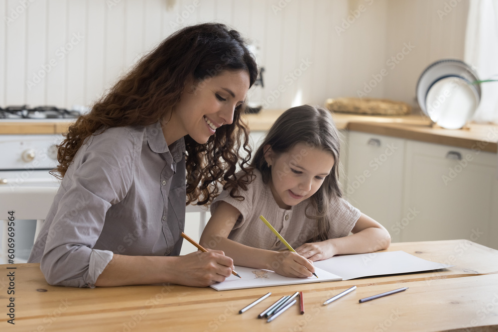 Φωτογραφία Cheerful mom and focused kid girl drawing cartoon sketches in paper album, using