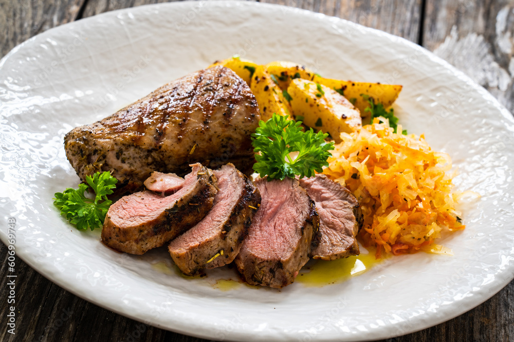 Grilled pork loin steaks with fried potatoes and sauerkraut salad on wooden table
Grilled pork loin steaks with fried potatoes and sauerkraut salad on wooden table