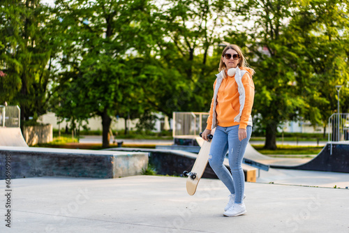 Young woman walking with skateboard in skate park