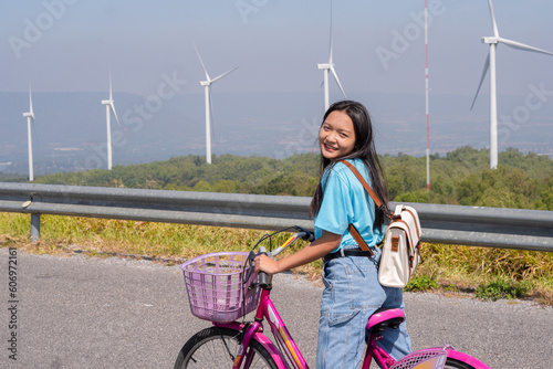 Young girl ride a bike on the road at the mountain with Wind Turbine, Khao Yai Thieng Electric Wind Turbine Thailand. photo