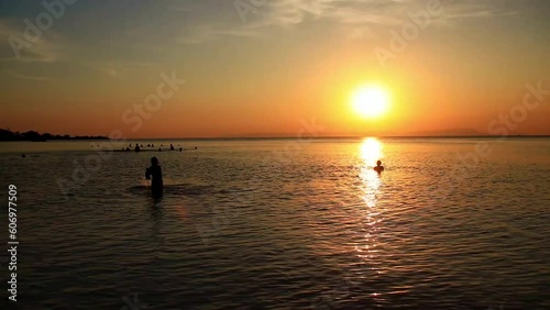 Idyllic summer scene of people silhouettes swimming and enjoying the sea and sunset in Koh Sdach Island Cambodia, popular tourist destination photo