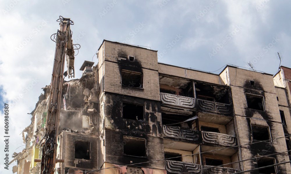 Excavator with hydraulic crusher at the demolition of a residential building. City renewal. Dismantling, destruction of a high-rise multi-storey building for reconstruction. Debris clearing.