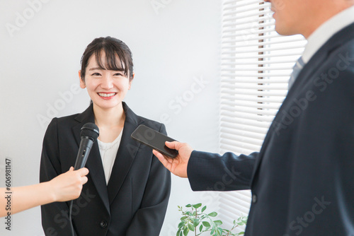 囲み取材をする報道陣と記者会見をする笑顔のアジア人女性
 photo