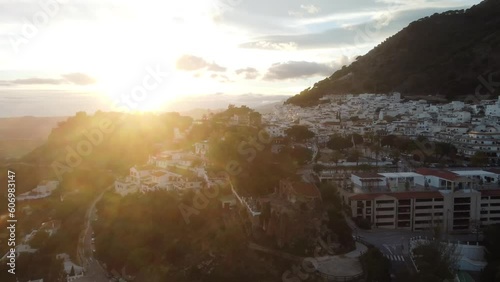 Bright sunset above white color town of Mijas in Spain, aerial orbit view
