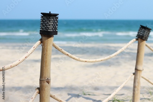 Lamps on bamboo fence posts on the beach.