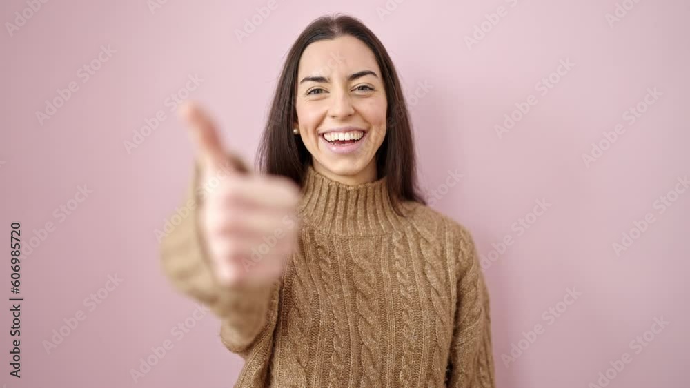 Young beautiful hispanic woman smiling with thumbs up over isolated pink background Young beautiful hispanic woman smiling with thumbs up over isolated pink background