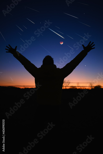 Silhouette of a man with Milky Way starry skies, Moon eclipse and meteor shower.