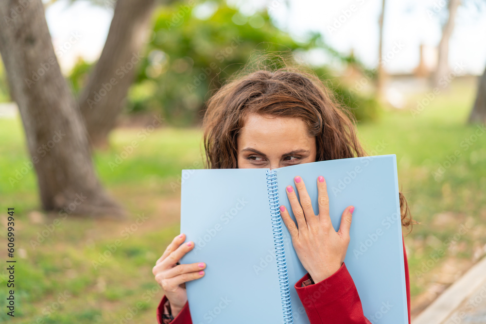 Young caucasian woman at outdoors holding a notebook Young caucasian woman at outdoors holding a notebook