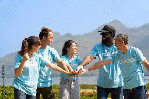 Group of happy diverse volunteers joining stacked hands together with smiles to show the power of unity in social environment charity working team, key success in making future a better world