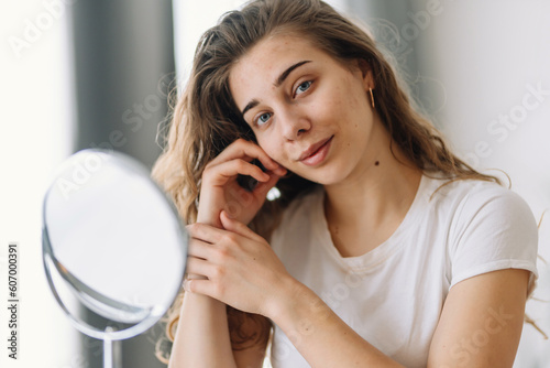 Beautiful  woman with problem skin looking into mirror. Dermatology. Allergic reaction from cosmetic  red spot or rash on face. Beauty care from skin problem.