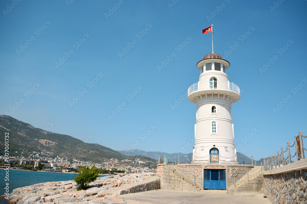 A lighthouse on the coast of the city with mountains on background, copy space A lighthouse on the coast of the city with mountains on background, copy space