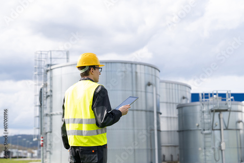 Engineer with digital tablet on a background of gas tanks.