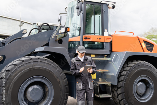 Serviceman with digital tablet on a background of the tractor 