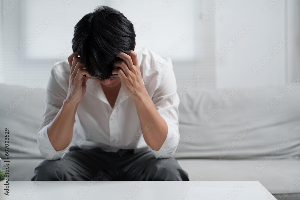 Young man sitting on sofa suffering from migraine after work.. Young man sitting on sofa suffering from migraine after work..