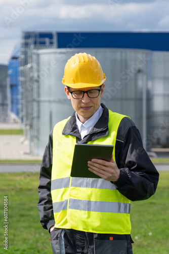 Engineer with digital tablet on a background of gas tanks. 