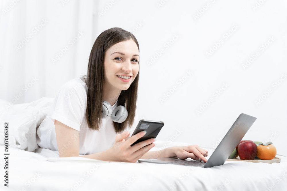 Young woman in the white shirt and pajama relaxing lying on a bed, she using mobile phone play social. Young woman in the white shirt and pajama relaxing lying on a bed, she using mobile phone play social.