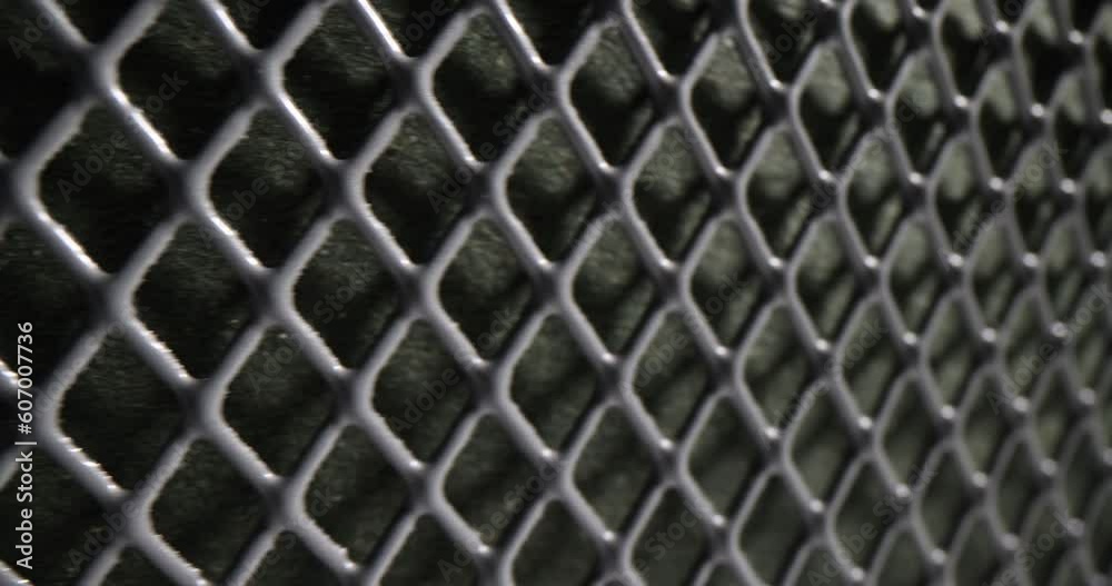 Grey perforated metal mesh as fence of private building and territory. Dark square grid pattern and texture as seamless design element slow motion Grey perforated metal mesh as fence of private building and territory. Dark square grid pattern and texture as seamless design element slow motion