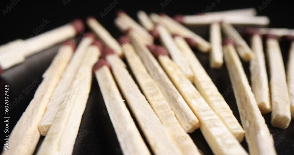 Thin aspen matches with red sulfur heads scattered randomly on black table in dark premise. Wooden matchsticks for getting fire or cooking purposes Thin aspen matches with red sulfur heads scattered randomly on black table in dark premise. Wooden matchsticks for getting fire or cooking purposes