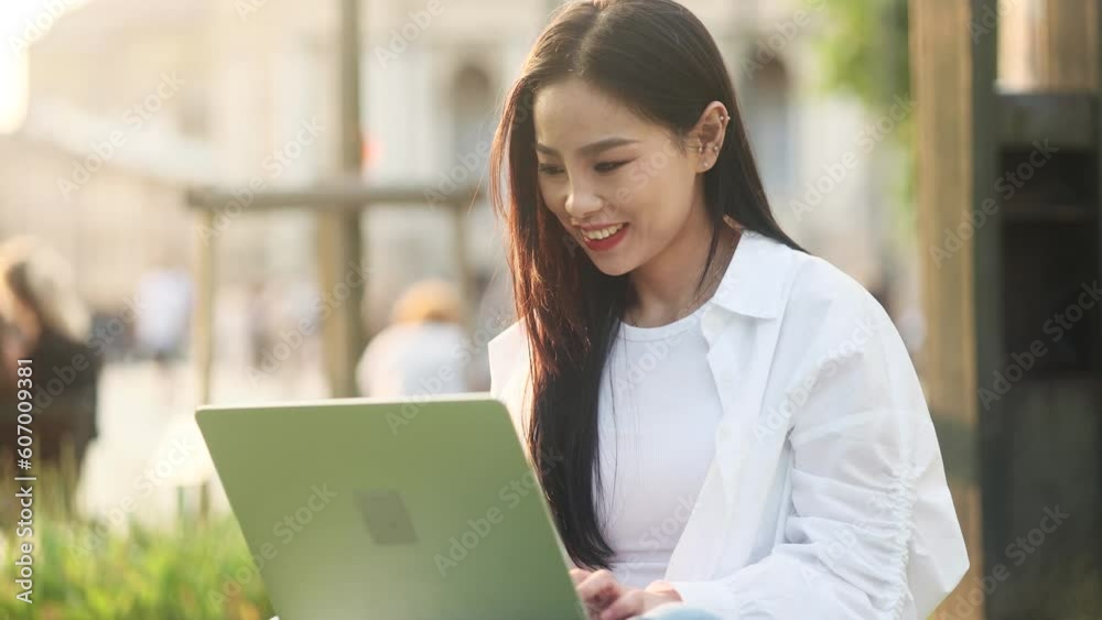 Pretty young asian woman freelancer or student working on laptop at green city street Busy focused girl having distance remote freelance work or education on computer outdoors alone Pretty young asian woman freelancer or student working on laptop at green city street Busy focused girl having distance remote freelance work or education on computer outdoors alone