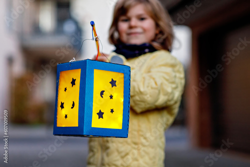 Closeup of little preschool kid girl holding selfmade traditional lanterns with candle for St. Martin procession. child happy about family parade in kindergarten. German tradition Martinsumzug photo