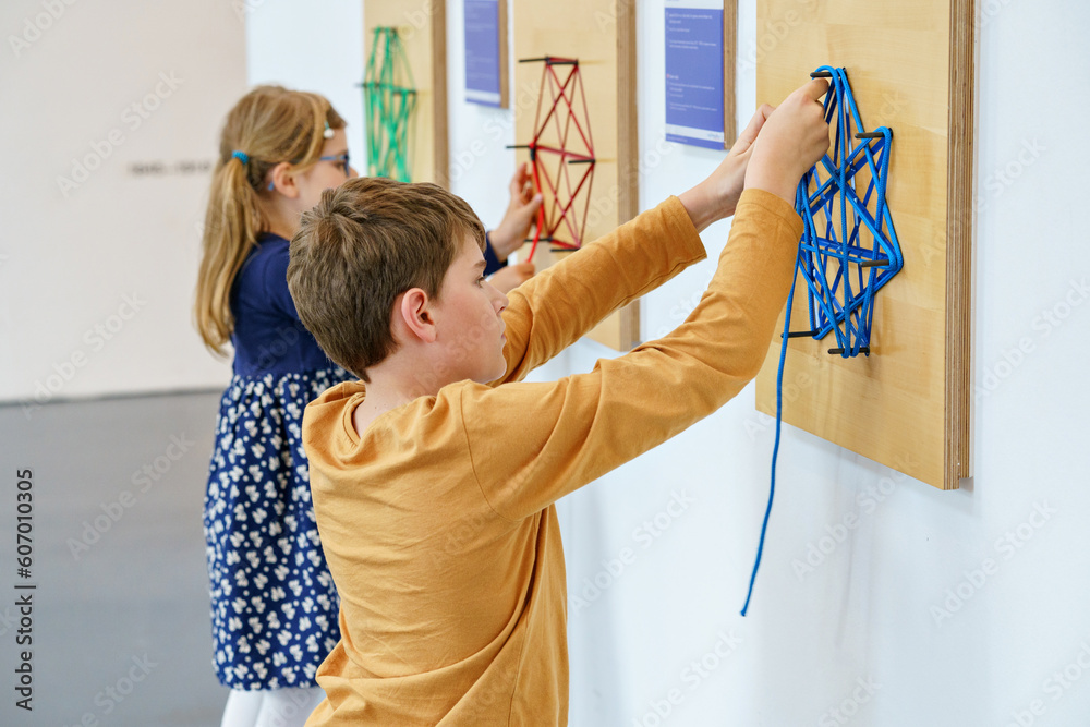© Irina Schmidt - Two little children playing logical games indoor. Boy and little girl having fun with building and creating geometric figures. with strings in child museum for maths